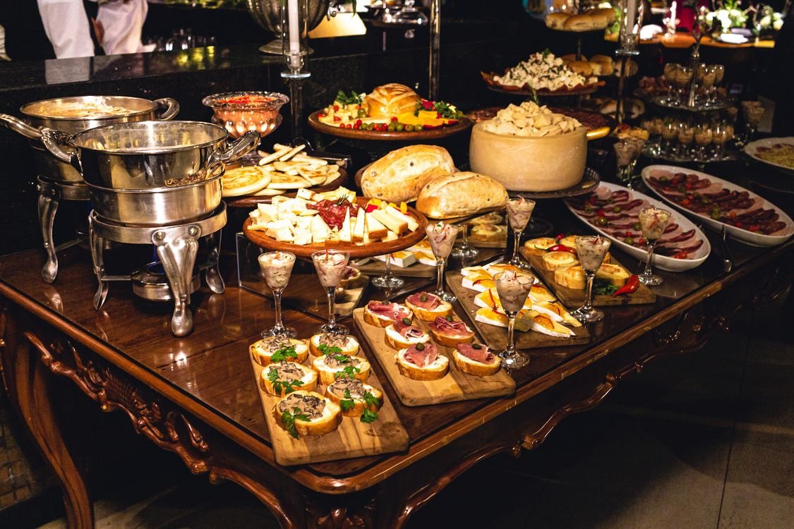 A catered buffet table with bread, cheese, meats, and finger foods.